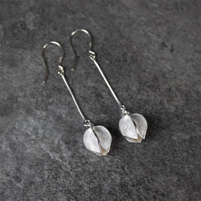 Kalevala Snow Flower Silver Earrings laying flat on grey surface