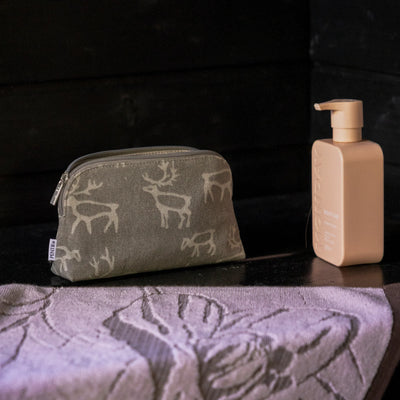 Cosmetic bag with deer pattern and beige bottle on a textured surface