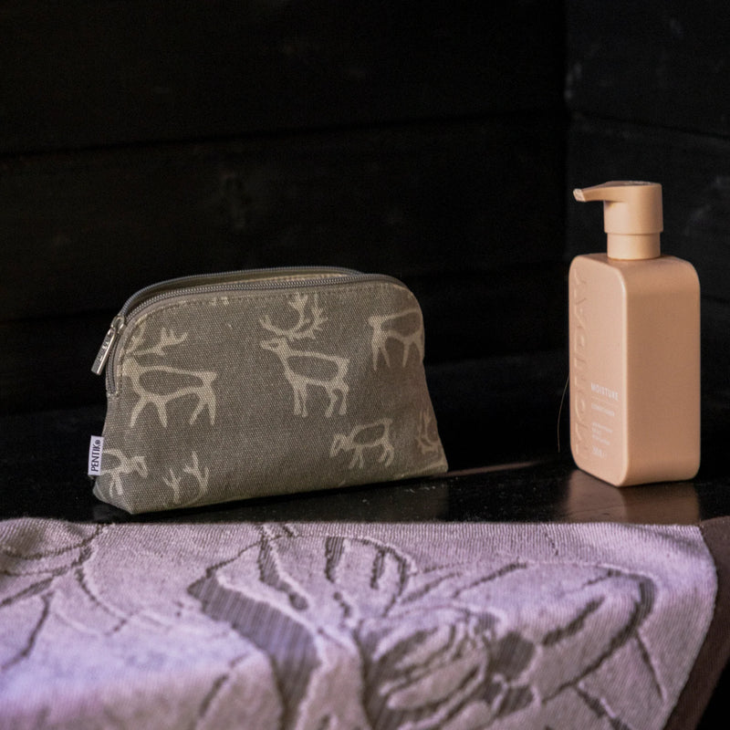 Cosmetic bag with deer pattern and beige bottle on a textured surface