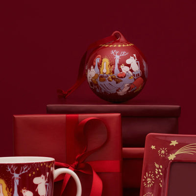 Decorative Christmas ball with reindeer and animals on a red background, surrounded by red gift boxes and mugs.