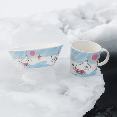 Moomin-themed bowl and mug on a snowy surface