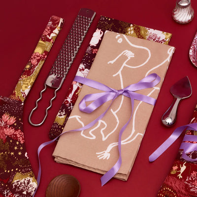 Decorative napkin with a purple ribbon on a red background with cutlery and patterned napkins.