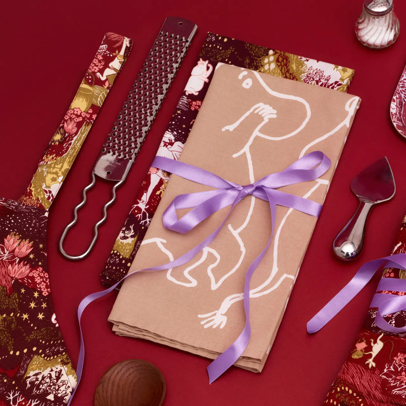 Decorative napkin with a purple ribbon on a red background with cutlery and patterned napkins.