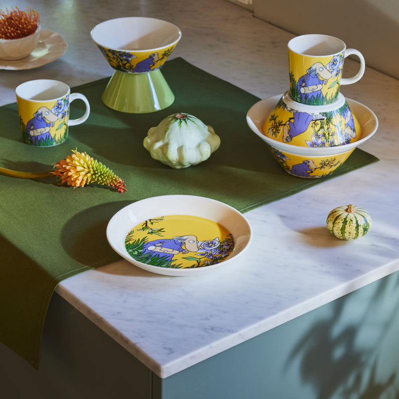 Colorful ceramic tableware set on a marble surface with green placemats.