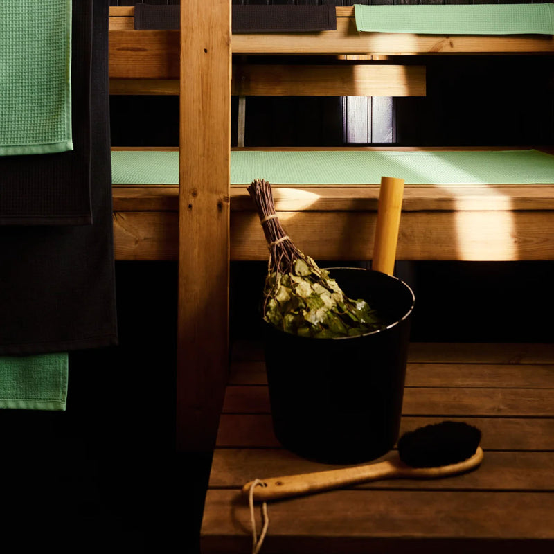 Bucket with leaves and brush on a wooden bench in a dimly lit room