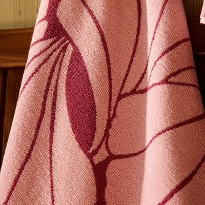 Close-up of a pink fabric with leaf-like patterns on a wooden surface.