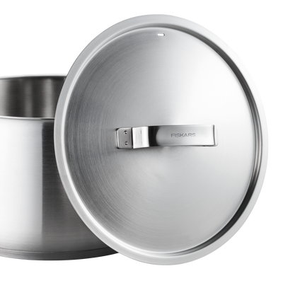 Stainless steel pot with lid featuring Fiskars branding on a white background