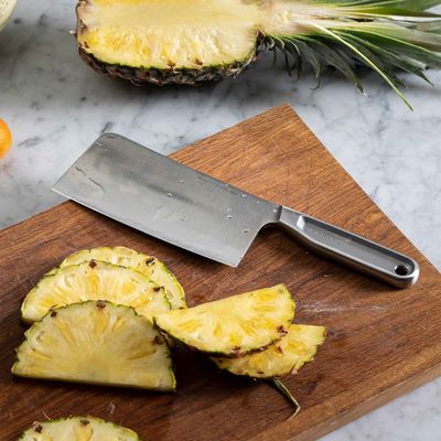 Sliced pineapple on a wooden cutting board with a knife
