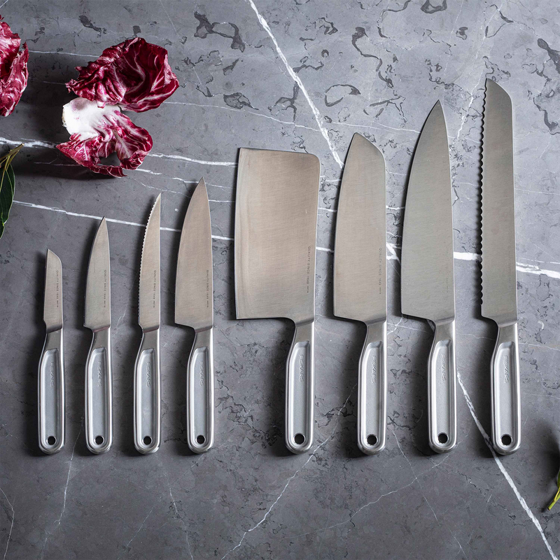 Set of kitchen knives on a gray surface with radicchio leaves.