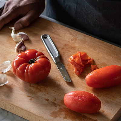 Tomatoes, garlic, and a knife on a wooden cutting board