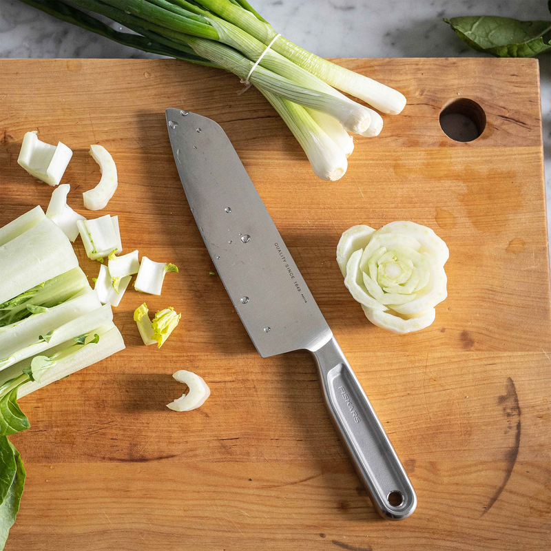 Chopped green onions on a wooden cutting board with a knife