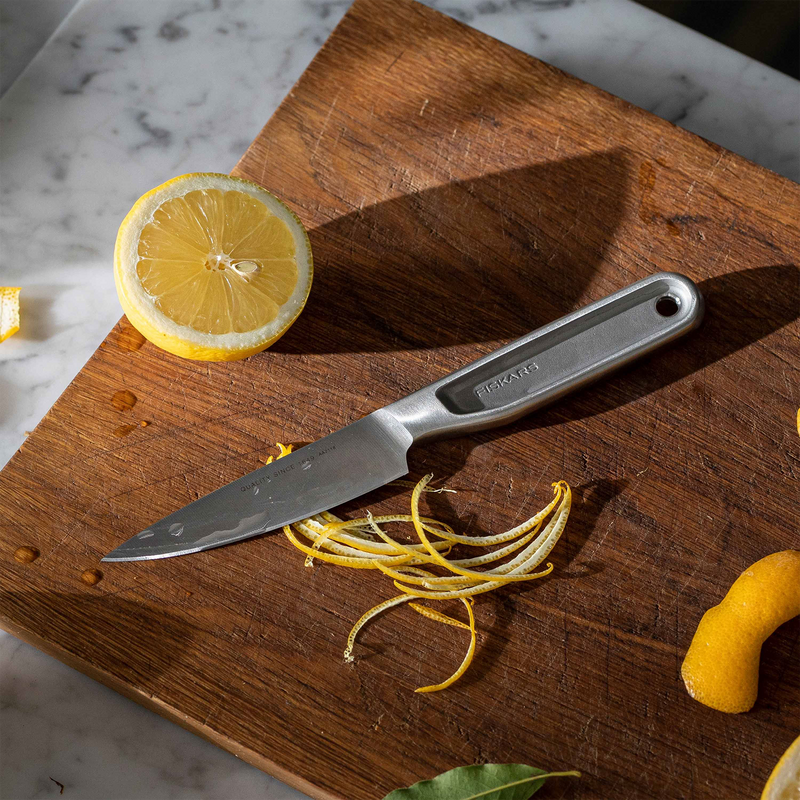 Knife on a wooden cutting board with lemon halves and zest