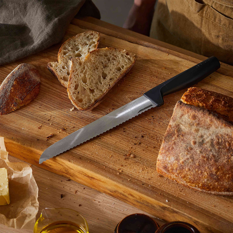 Sliced bread on a wooden cutting board with a serrated knife
