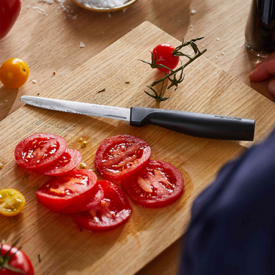 Sliced tomatoes on a wooden cutting board with a knife
