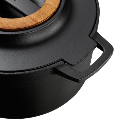 Black cast iron pot with wooden lid on a white background