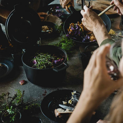 People preparing food on a table with various ingredients and utensils.