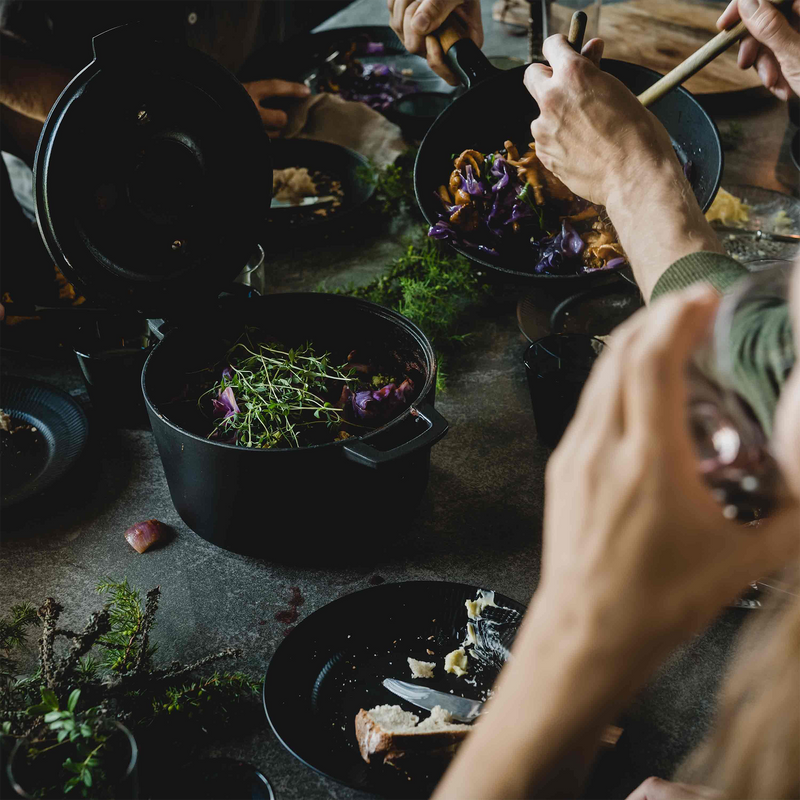 People preparing food on a table with various ingredients and utensils.