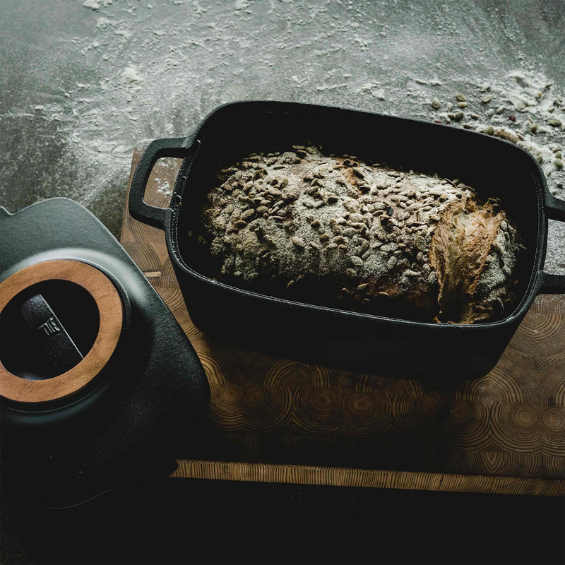 Loaf of bread in a black baking dish on a textured surface