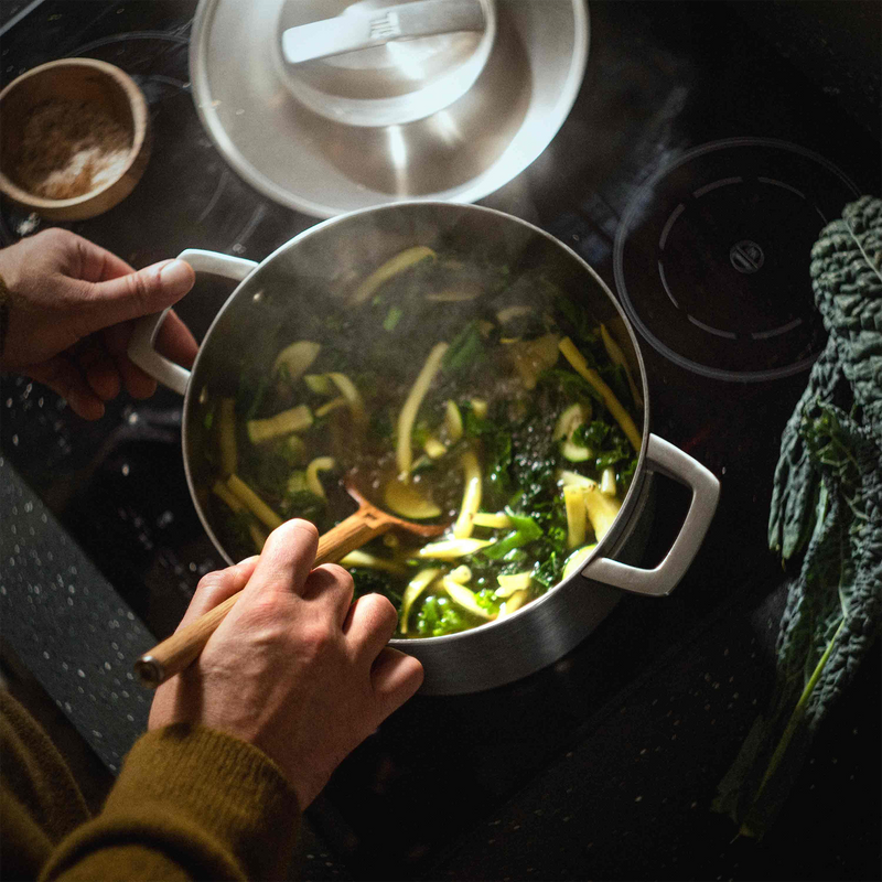 Person cooking vegetables in a pan on a stove