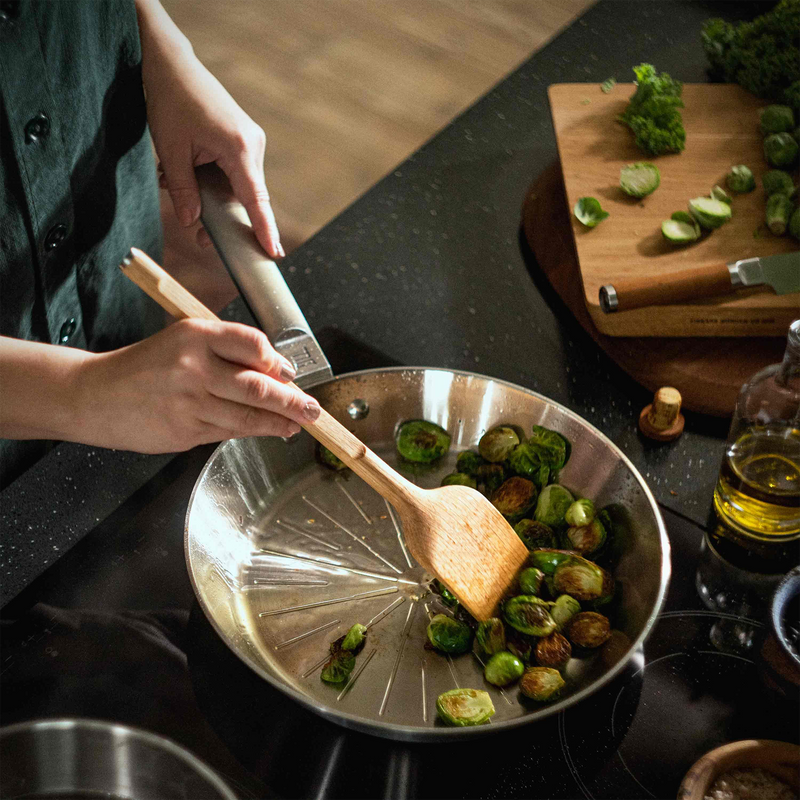 Person cooking brussels sprouts in a pan on a stove