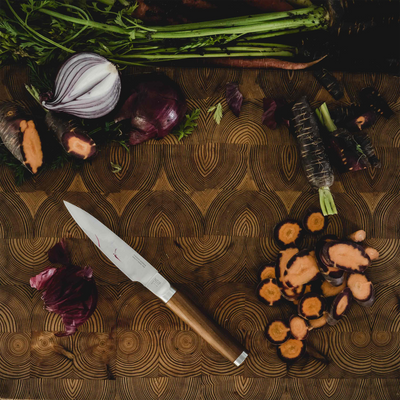 Vegetables and a knife on a wooden cutting board