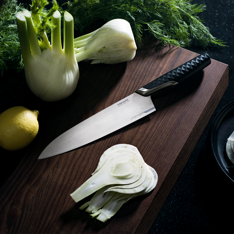 Fennel bulb with slices on a wooden cutting board with a knife and lemon.