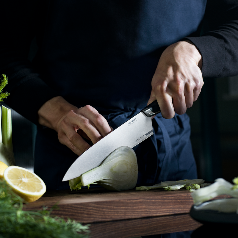 Person cutting vegetables on a wooden board with a knife