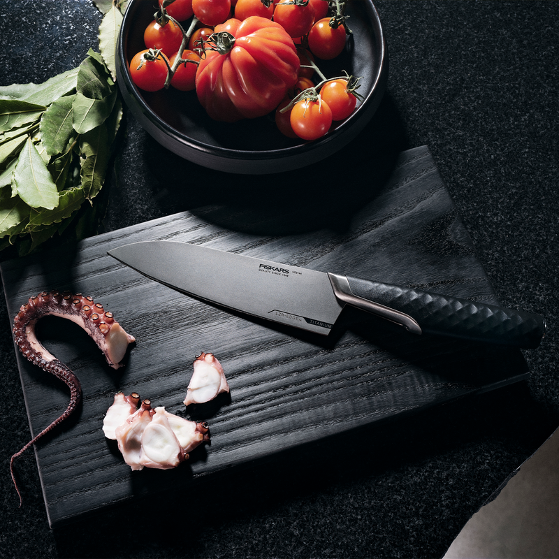 Forked knife on a dark surface with tomatoes and octopus pieces