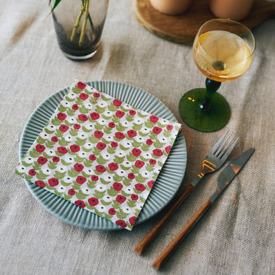Table setting with floral napkin, plate, wine glass, fork, and knife on a textured tablecloth.