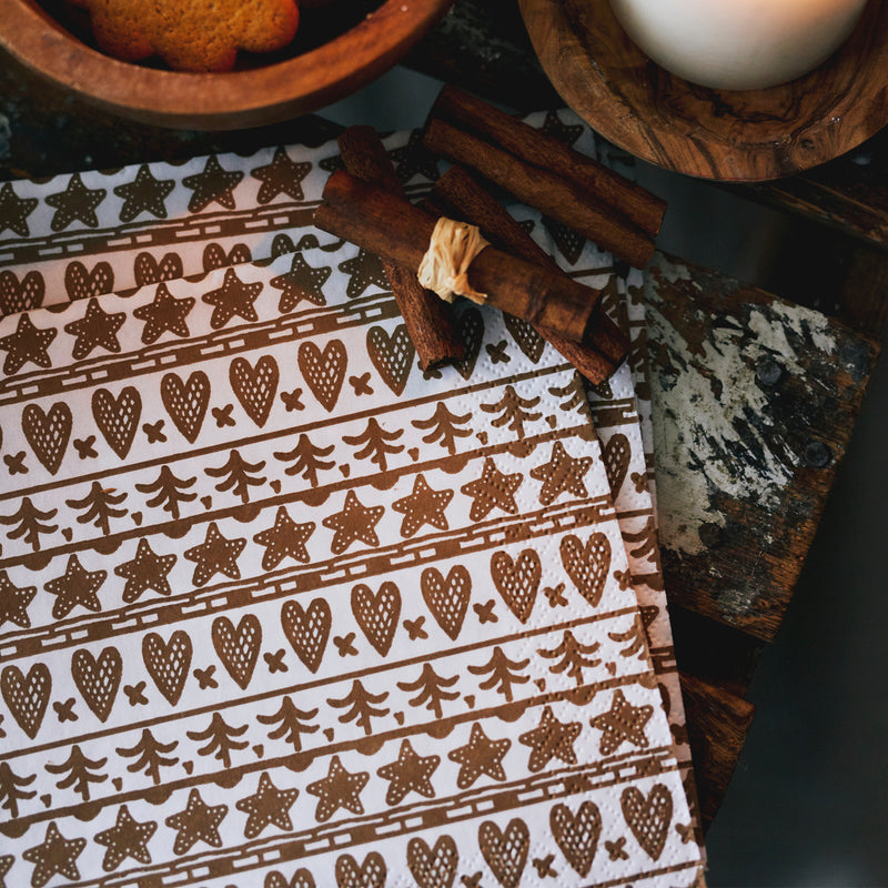 Patterned paper with cinnamon sticks and a wooden spatula on a dark surface