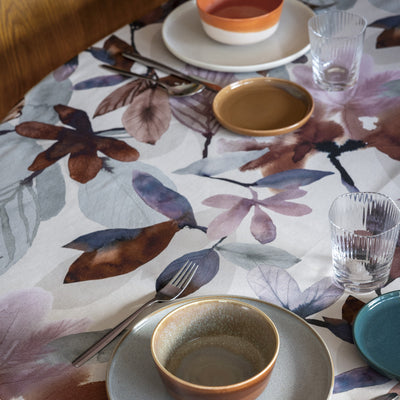 Table setting with floral tablecloth, ceramic bowls, and cutlery.