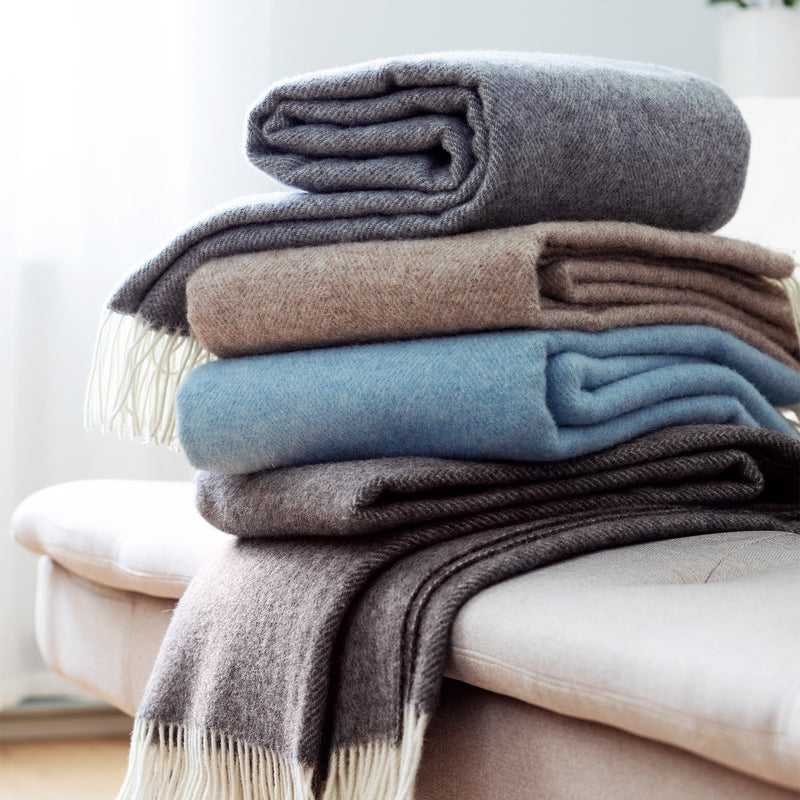 Stack of folded blankets in various colors on a white surface
