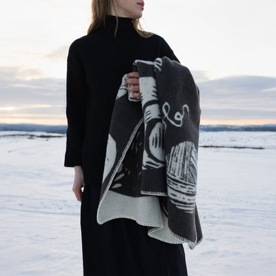 Person wearing a black turtleneck and patterned scarf in a snowy landscape