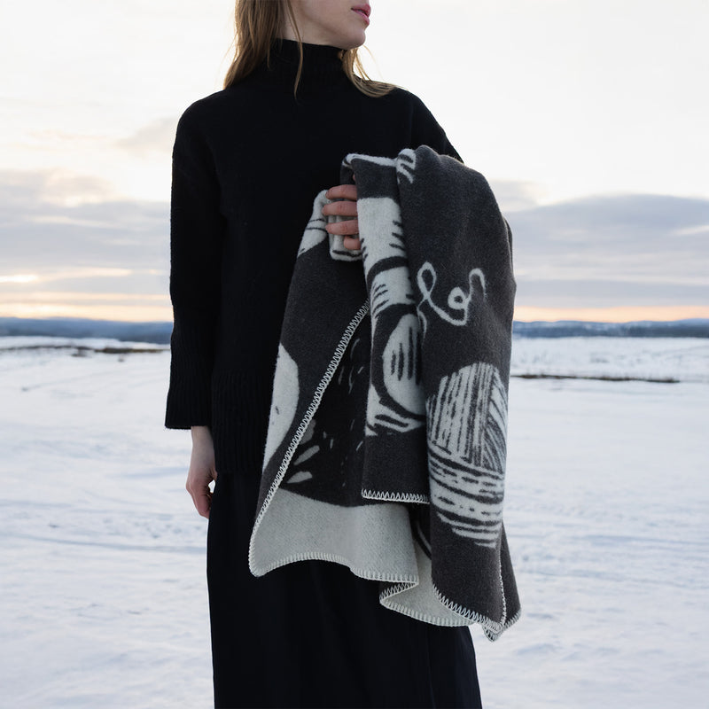 Person wearing a black turtleneck and patterned scarf in a snowy landscape