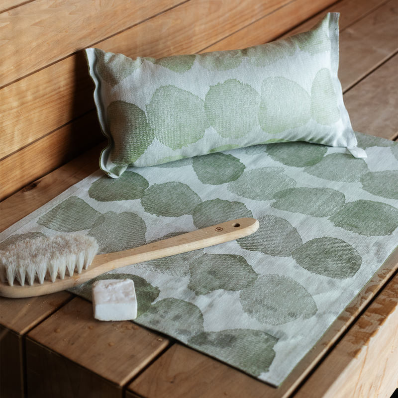 Green patterned towel with a brush and soap on a wooden surface