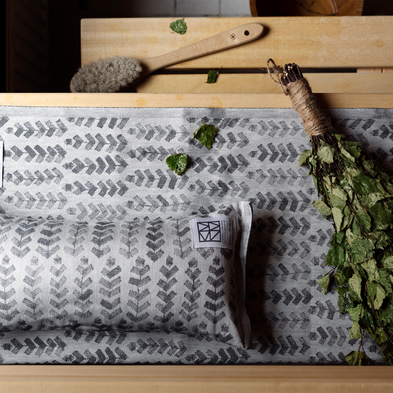 Patterned fabric with a label on a wooden surface with green leaves and a brush.