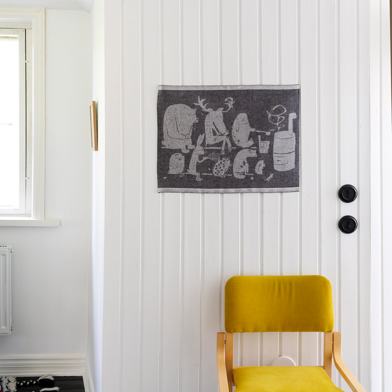 Yellow chair in front of a white door with a decorative black and white tapestry.