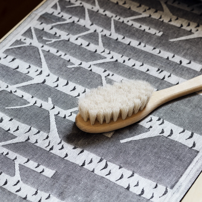 Wooden brush with white bristles on a gray and white patterned fabric background