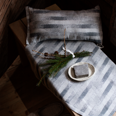 Striped fabric with a plate of soap and greenery on a wooden surface