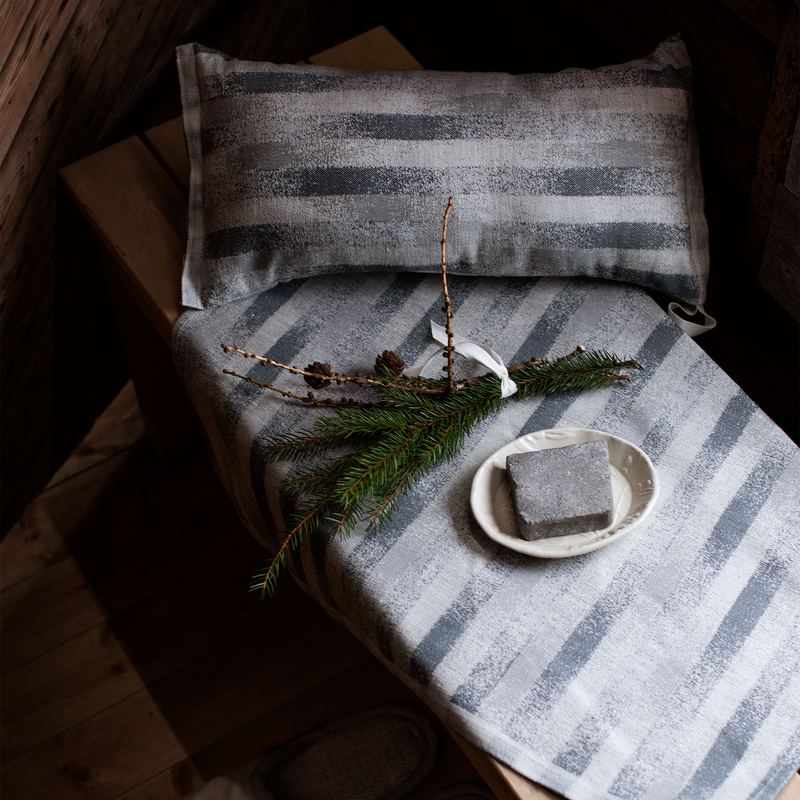 Striped fabric with a plate of soap and greenery on a wooden surface