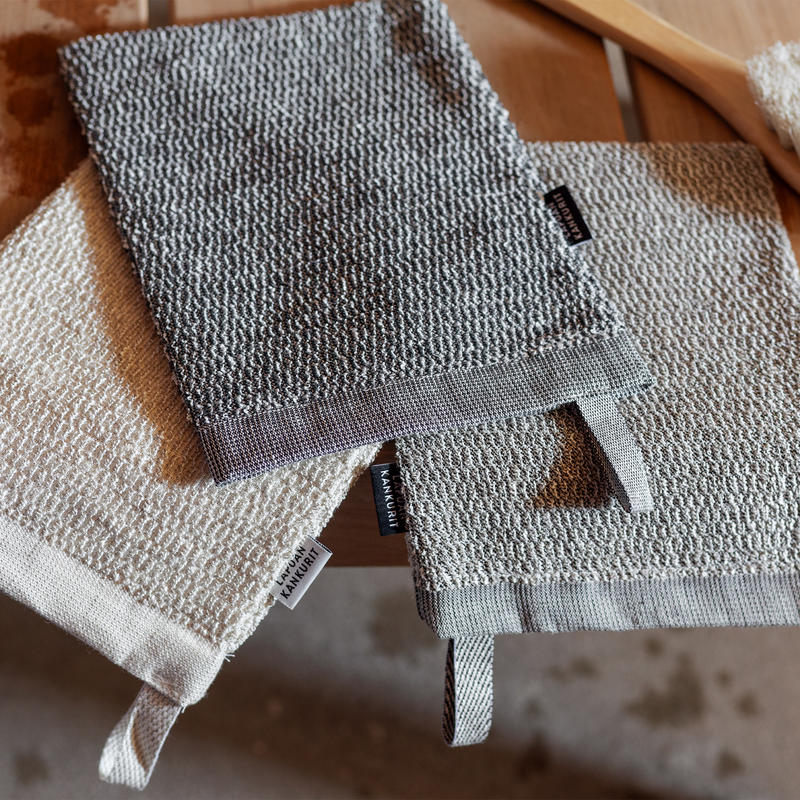 Three textured hand towels stacked on a wooden surface with visible brand labels.