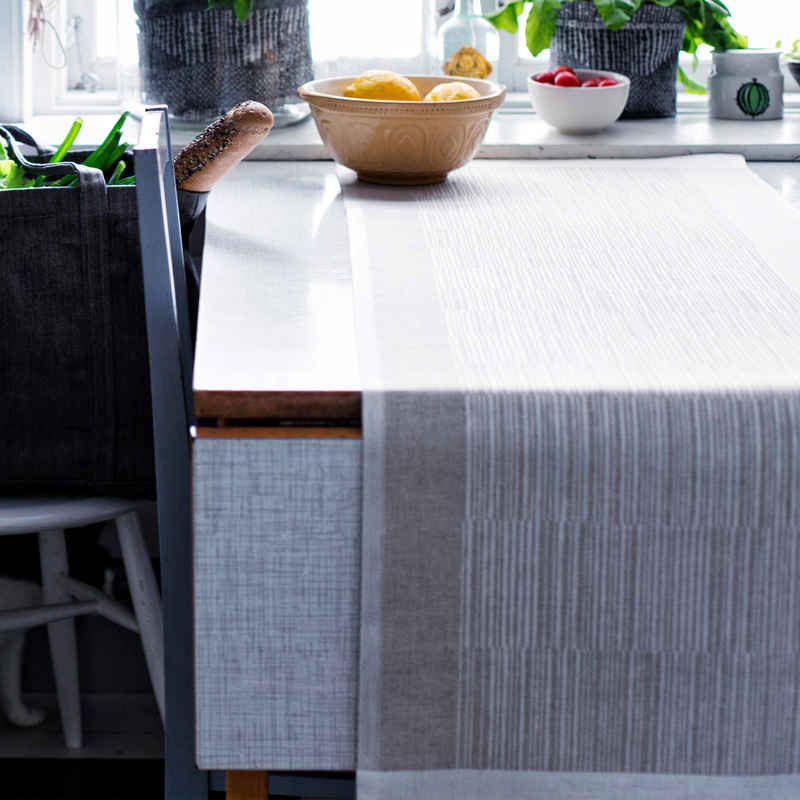 Kitchen counter with a gray tablecloth, bowls of fruit, and a plant.