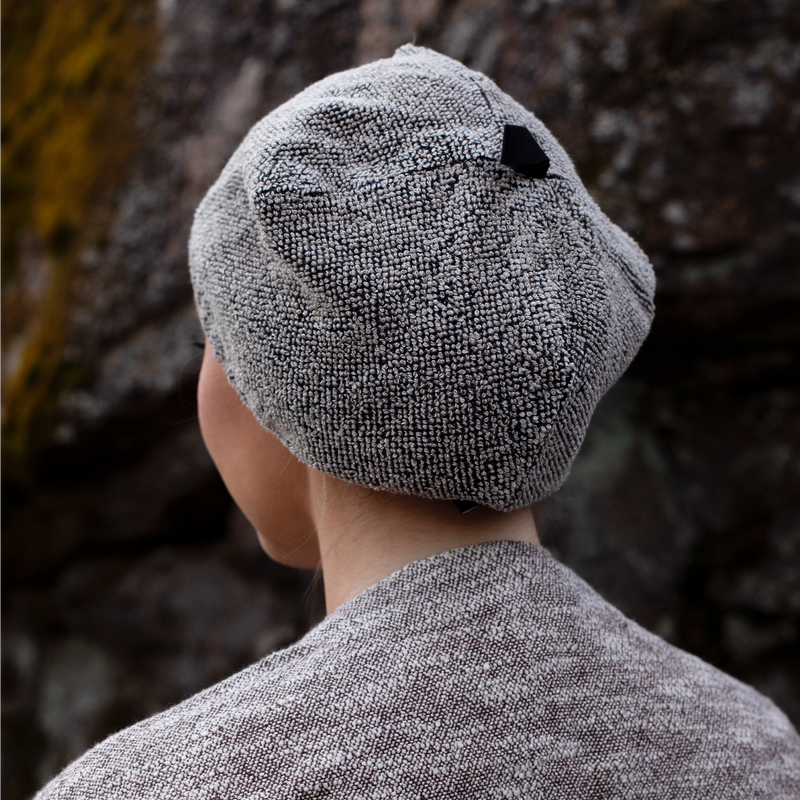 Person wearing a textured gray hat and coat against a natural background