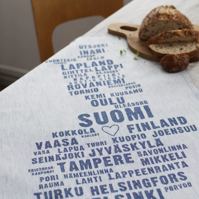 Tablecloth with text of Finnish cities on a table with bread