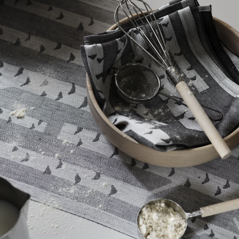 Kitchen utensils including a whisk, measuring spoon, and bowl on a patterned surface.