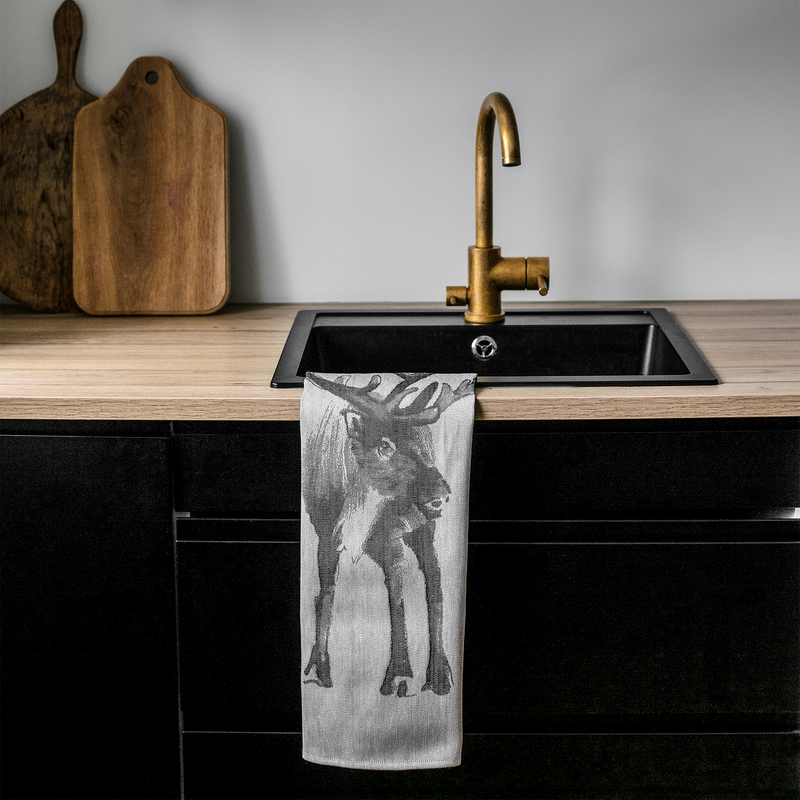 Kitchen sink with gold faucet and towel with deer design on wooden counter