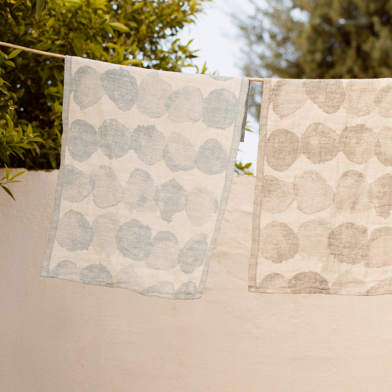 Two patterned towels hanging on a line with trees in the background