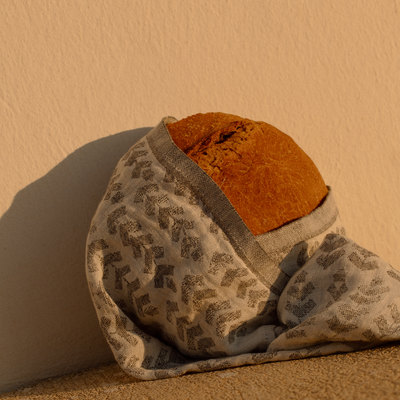 Brown bread wrapped in a patterned cloth against a beige wall.