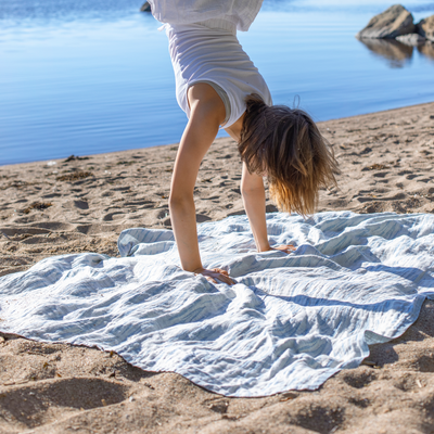 Person doing a handstand on a towel by a body of water