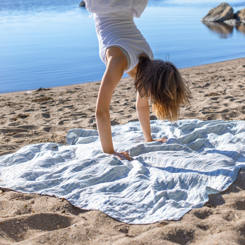 Person doing a handstand on a towel by a body of water